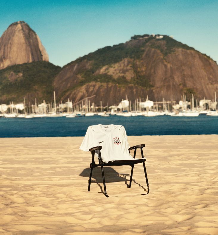 Nova camisa da Coleção Corinthians 50 anos pendurada em uma cadeira no meio da praia, com o mar no fundo