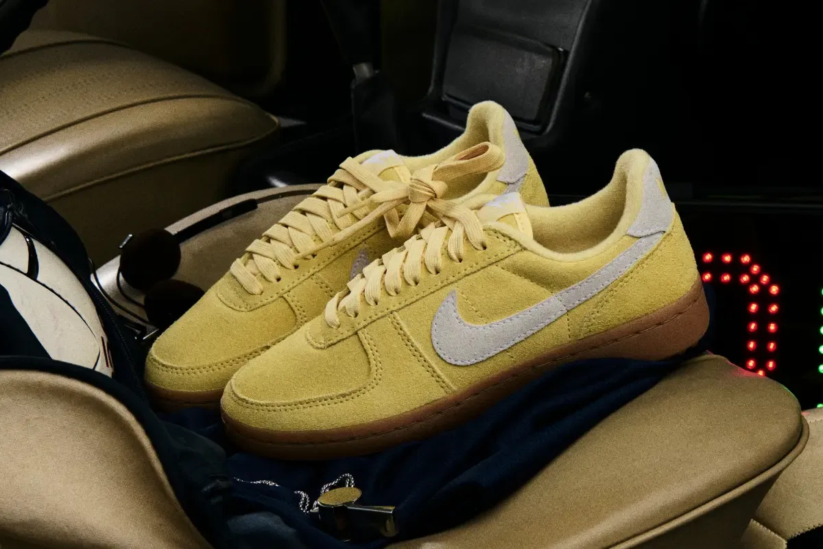 Par de tênis Nike amarelos posicionados sobre banco dentro de carro.