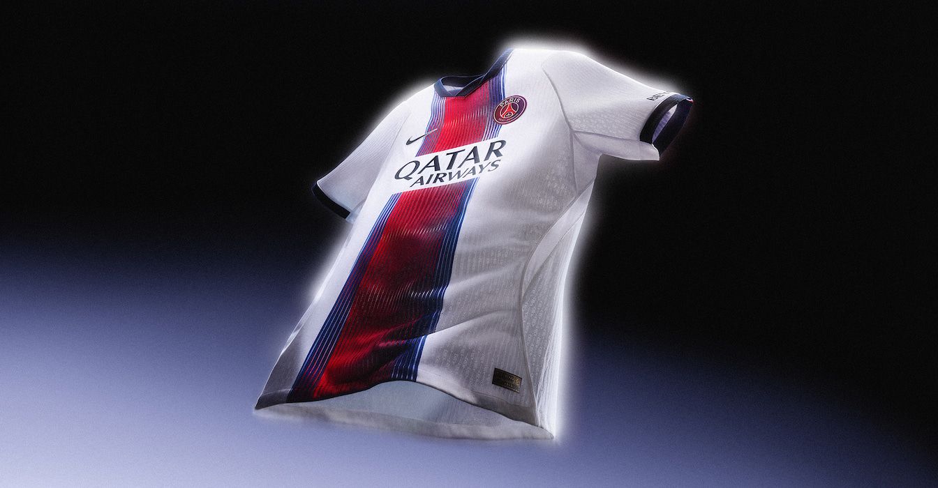 Uma camisa branca de futebol do Paris Saint-Germain flutuando contra um fundo escuro, com uma faixa central vermelha e azul.