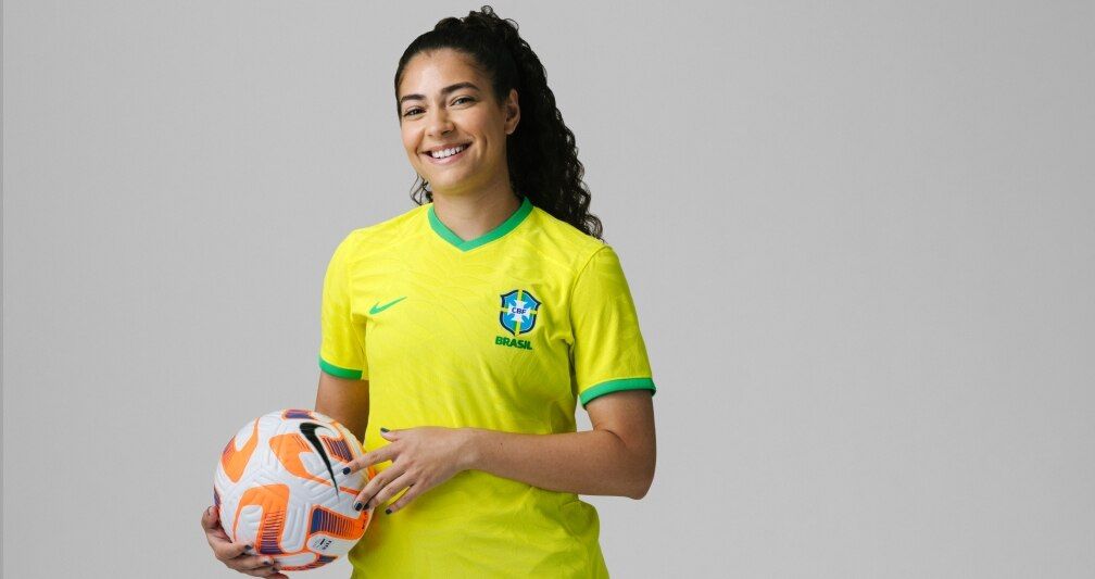 Angelina Alonso sorrindo enquanto segura uma bola de futebol da Nike.