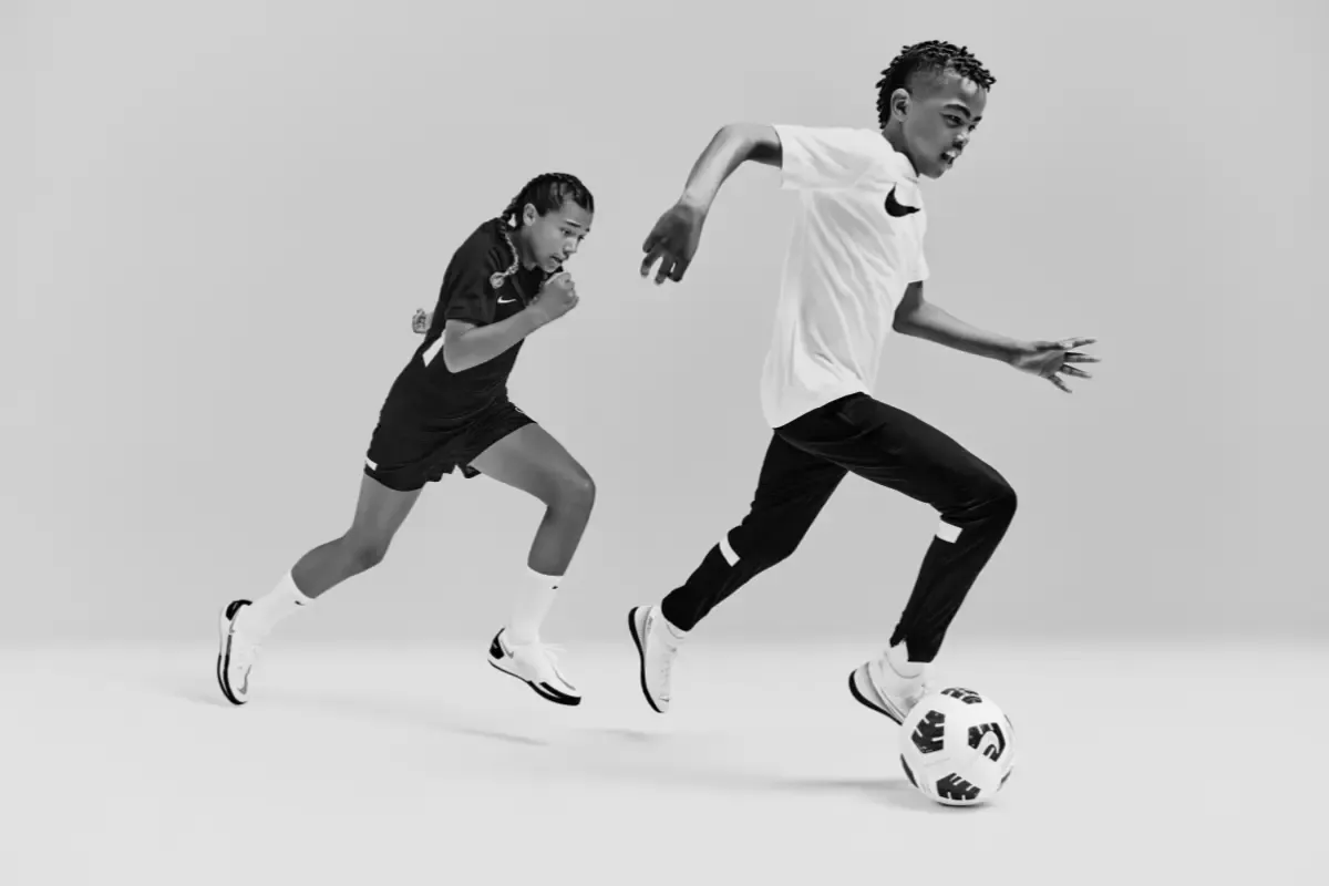 duas crianças correndo atrás de uma bola