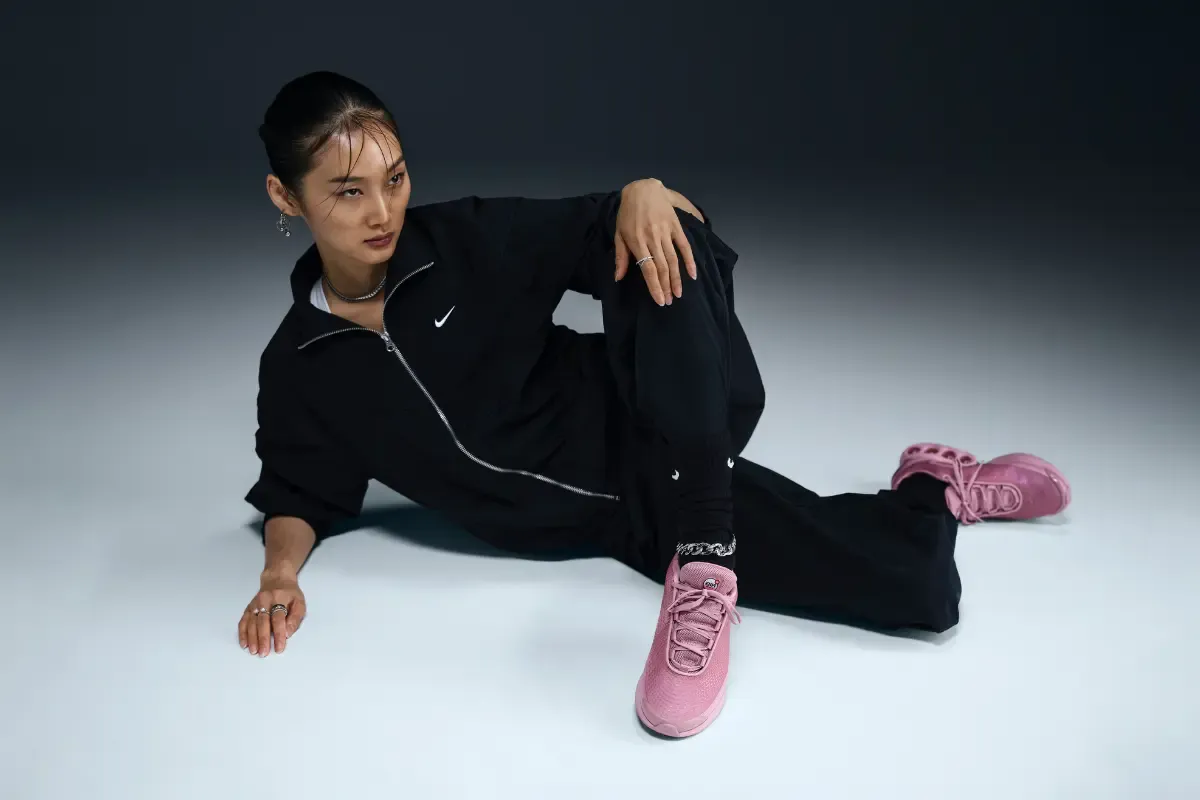 imagem de uma mulher sentada com roupa preta e tenis rosa