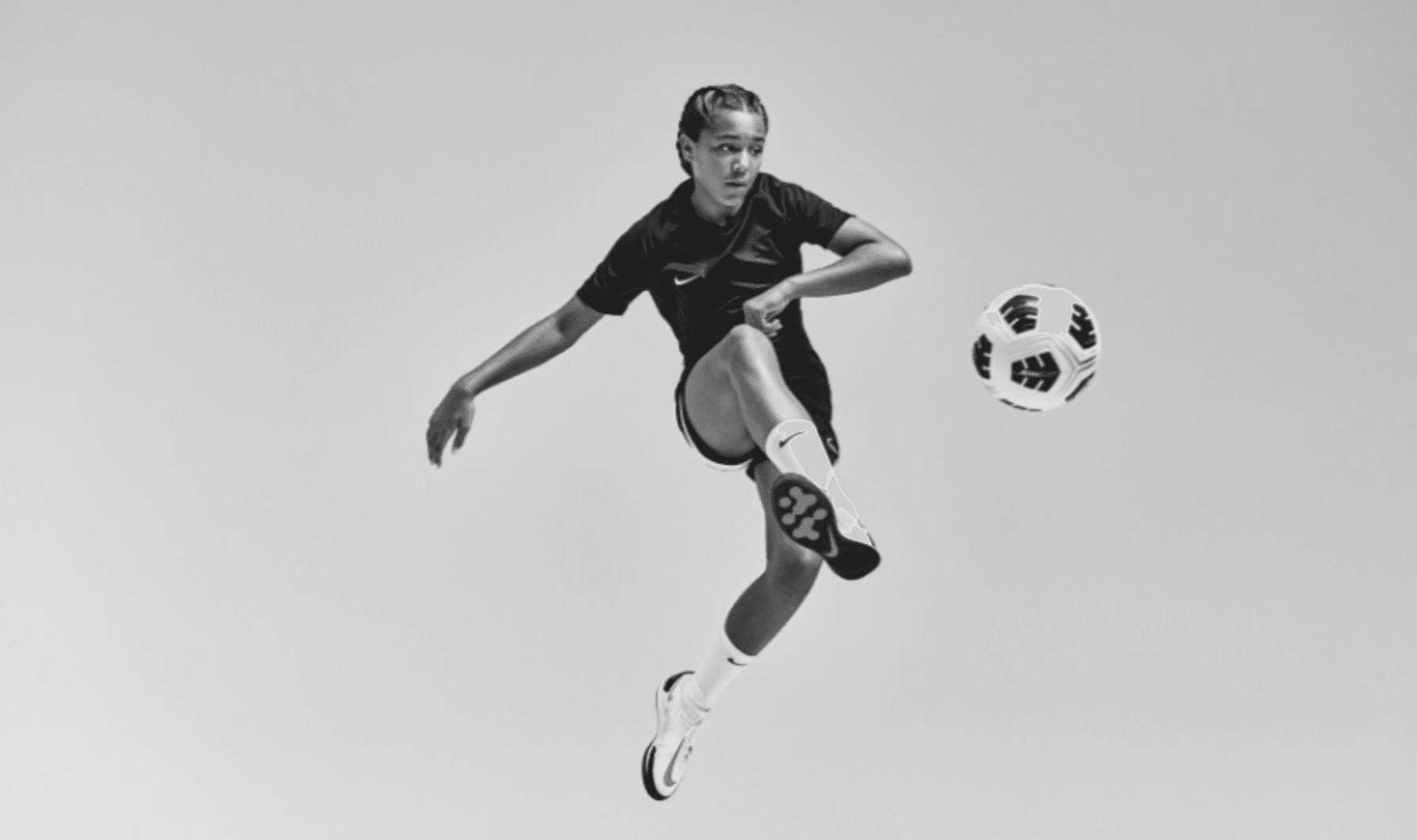 mulher chutando bola futebol chuteira nike feminino