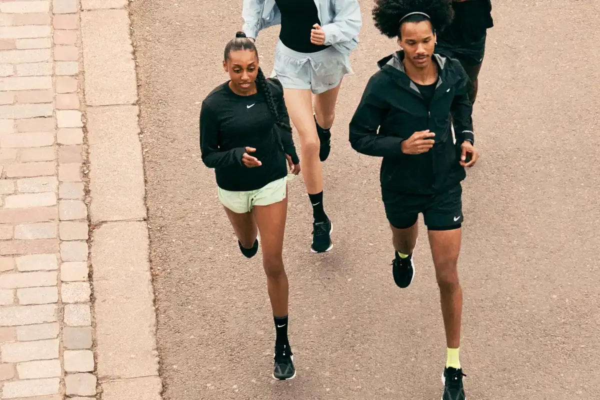Grupo de jovens corredores ao ar livre, vestindo roupas esportivas e tênis de corrida.