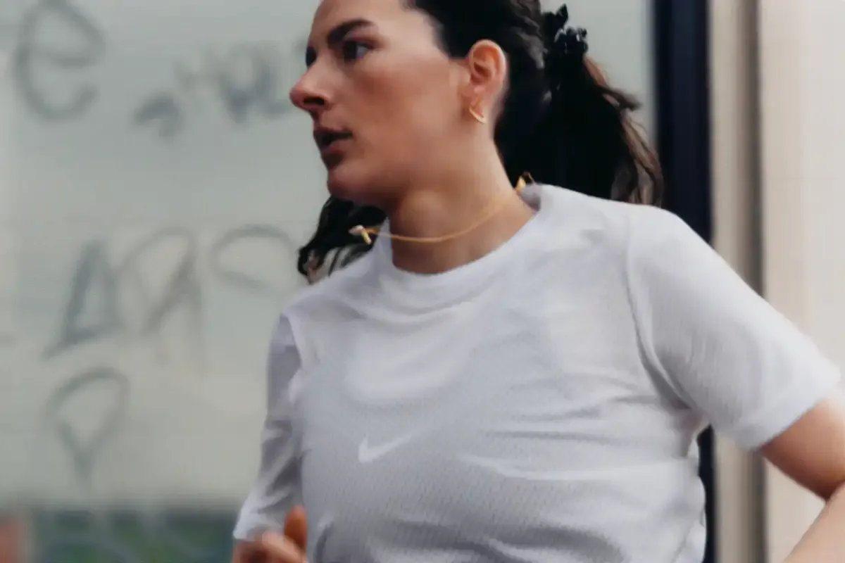 Imagem de uma mulher treinando na academia usando roupa de corrida branca.