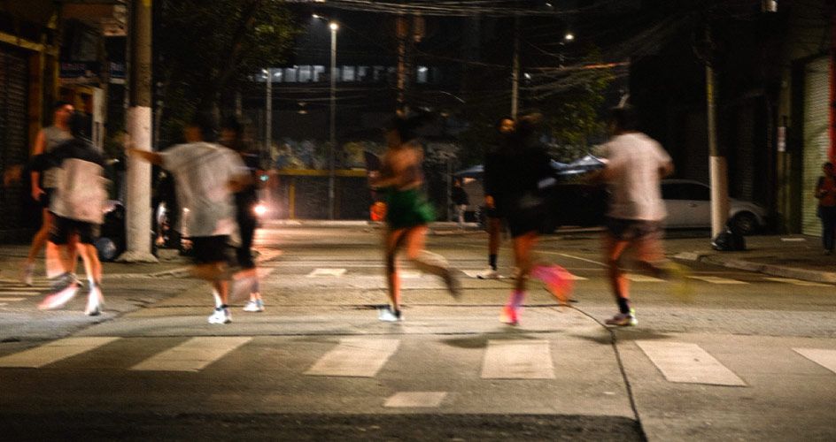 Pessoas correndo na rua à noite.