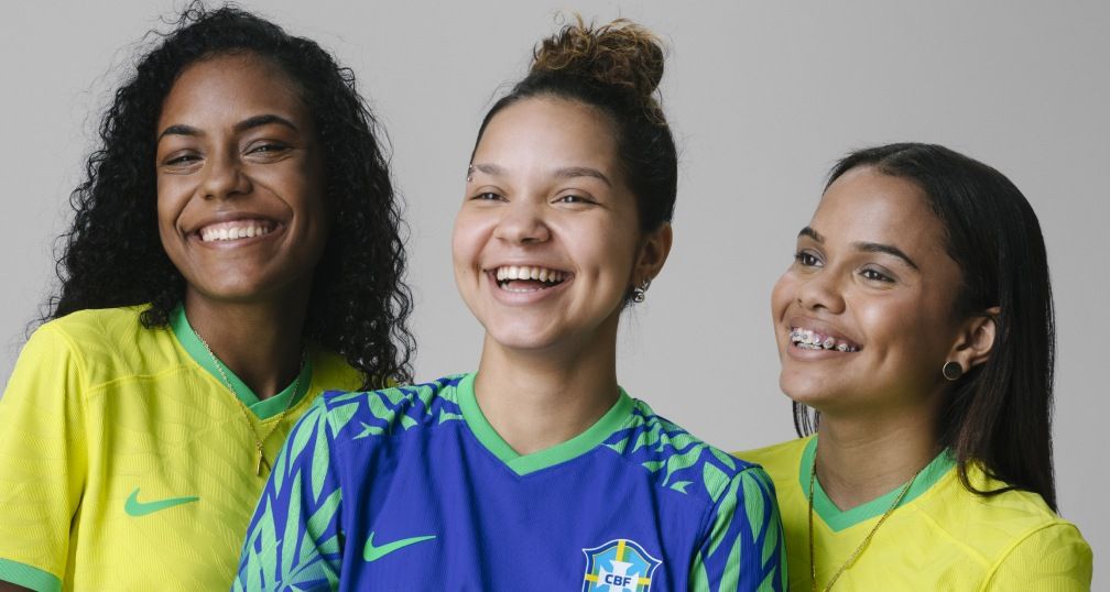 Três jovens com camisetas da seleção brasileira.