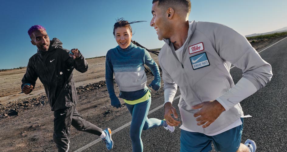 Três pessoas correndo numa estrada.